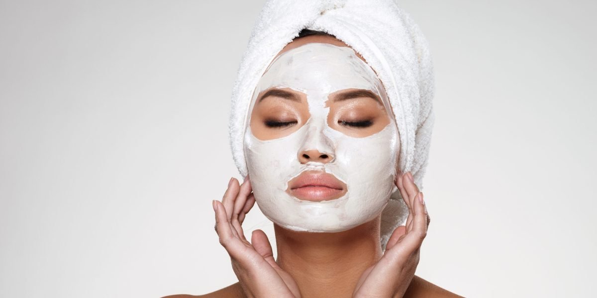 Portrait of beautiful lady with closed eyes and towel on her head put scrab on her face isolated
